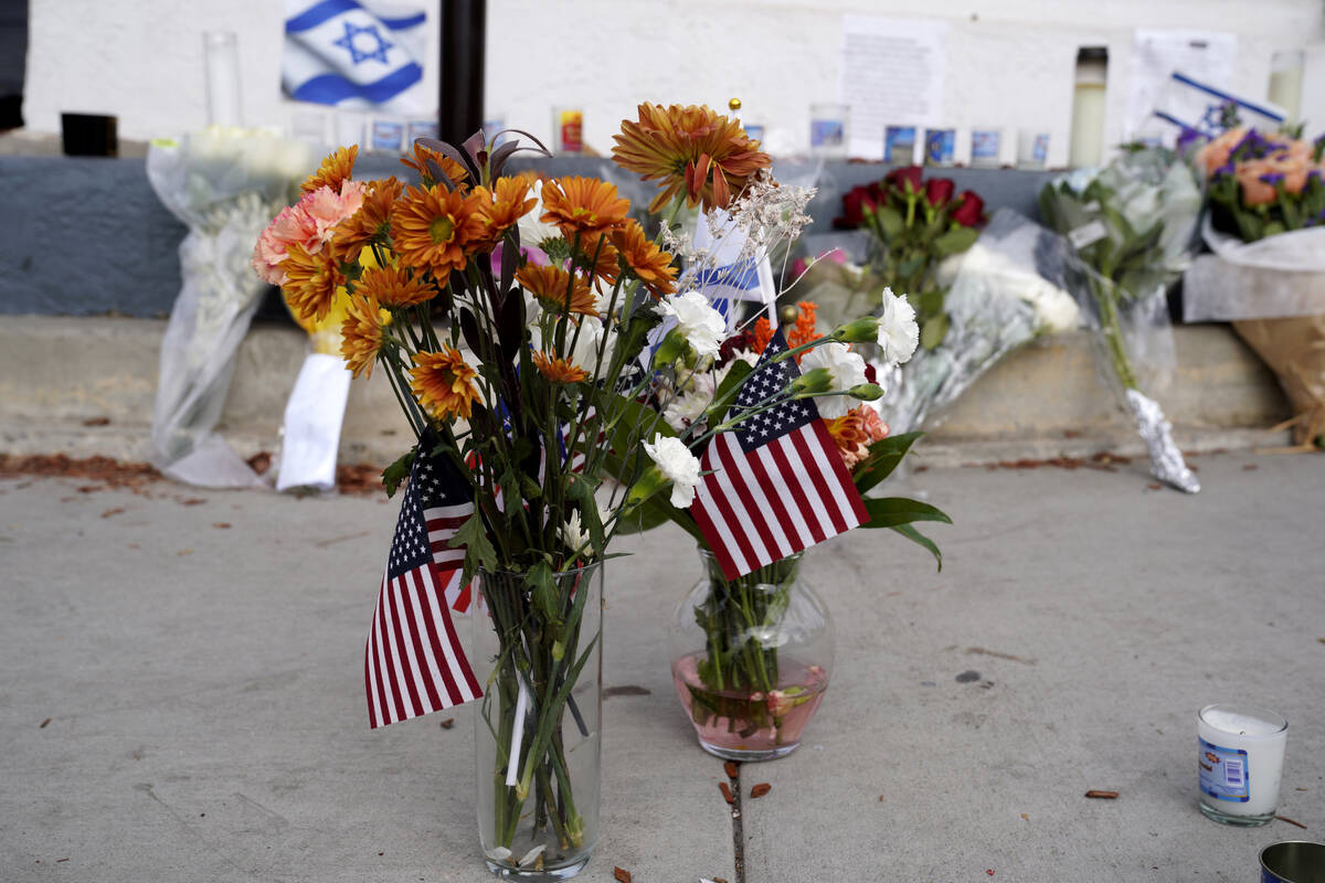 Flowers and flags are left at a makeshift shrine placed at the scene of a Sunday confrontation ...