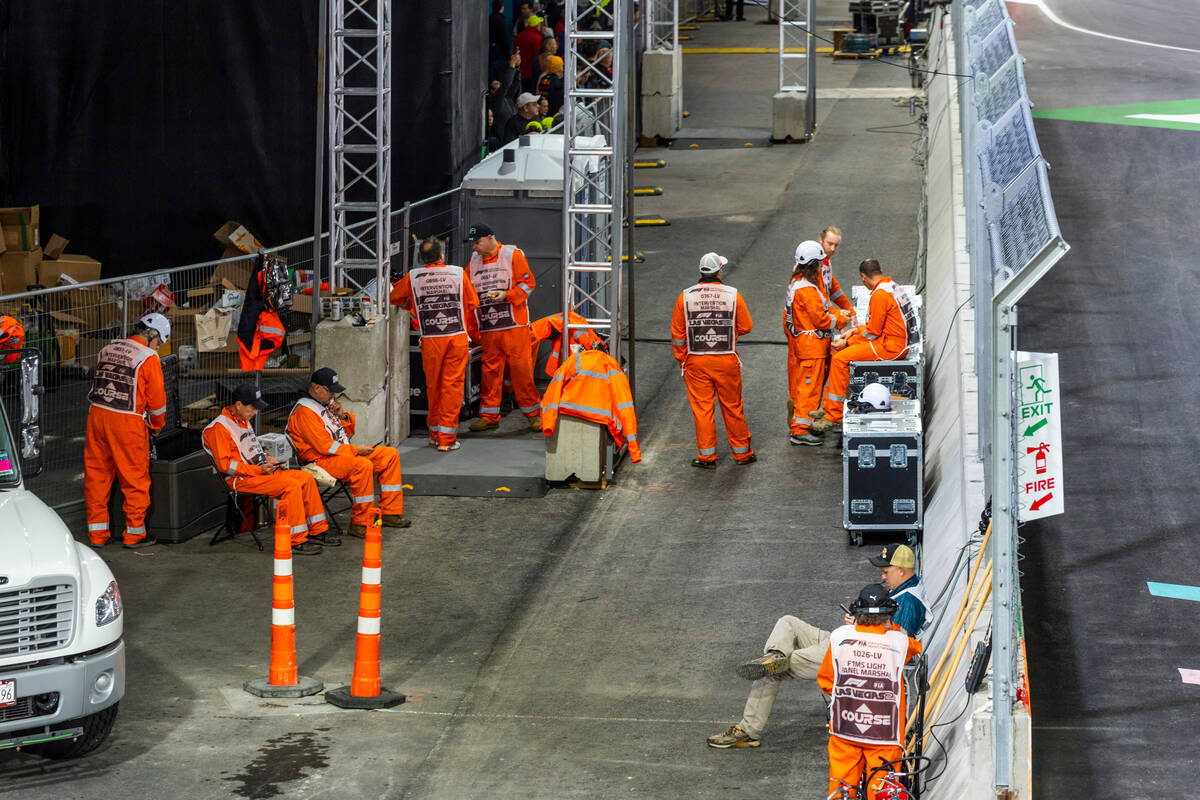 Track marshals await the delayed racing decision across from the pit building after the first p ...