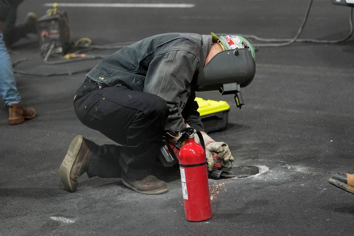 Work is performed on a manhole following the first practice session for the Formula One Las Veg ...