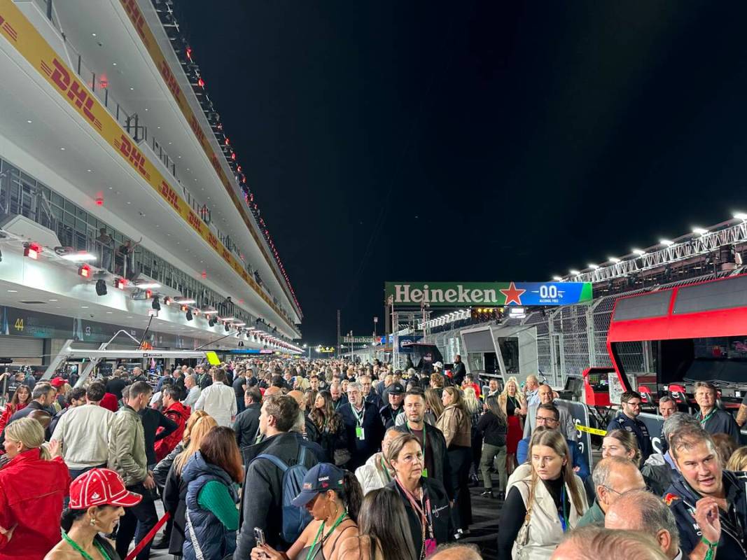 Race fans with suite-level access mill about the pit lane during the canceled practice session ...