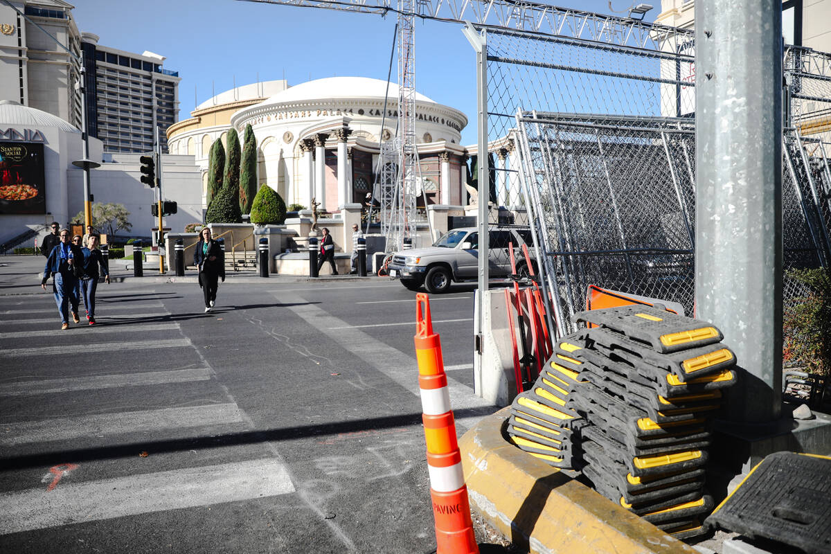 Pedestrians cross the Strip near equipment for the Formula 1 Las Vegas Grand Prix race on the S ...