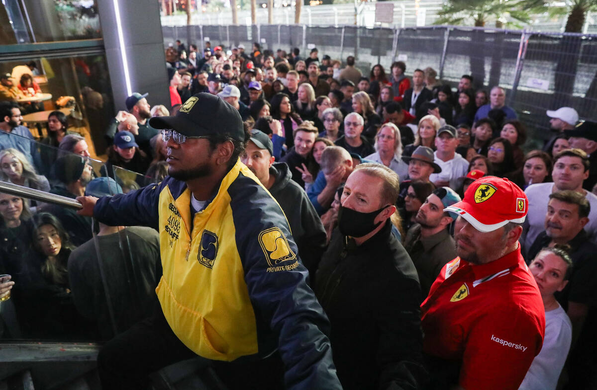 A security guard holds back people prior to the Formula 1 Las Vegas Grand Prix race on Saturday ...