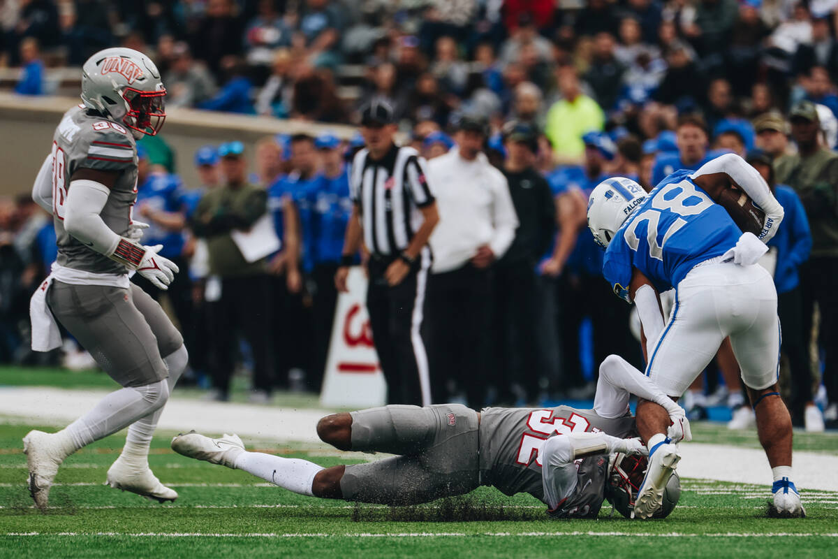 UNLV defensive back Ricky Johnson (32) pulls at the leg of Air Force running back Aiden Calvert ...