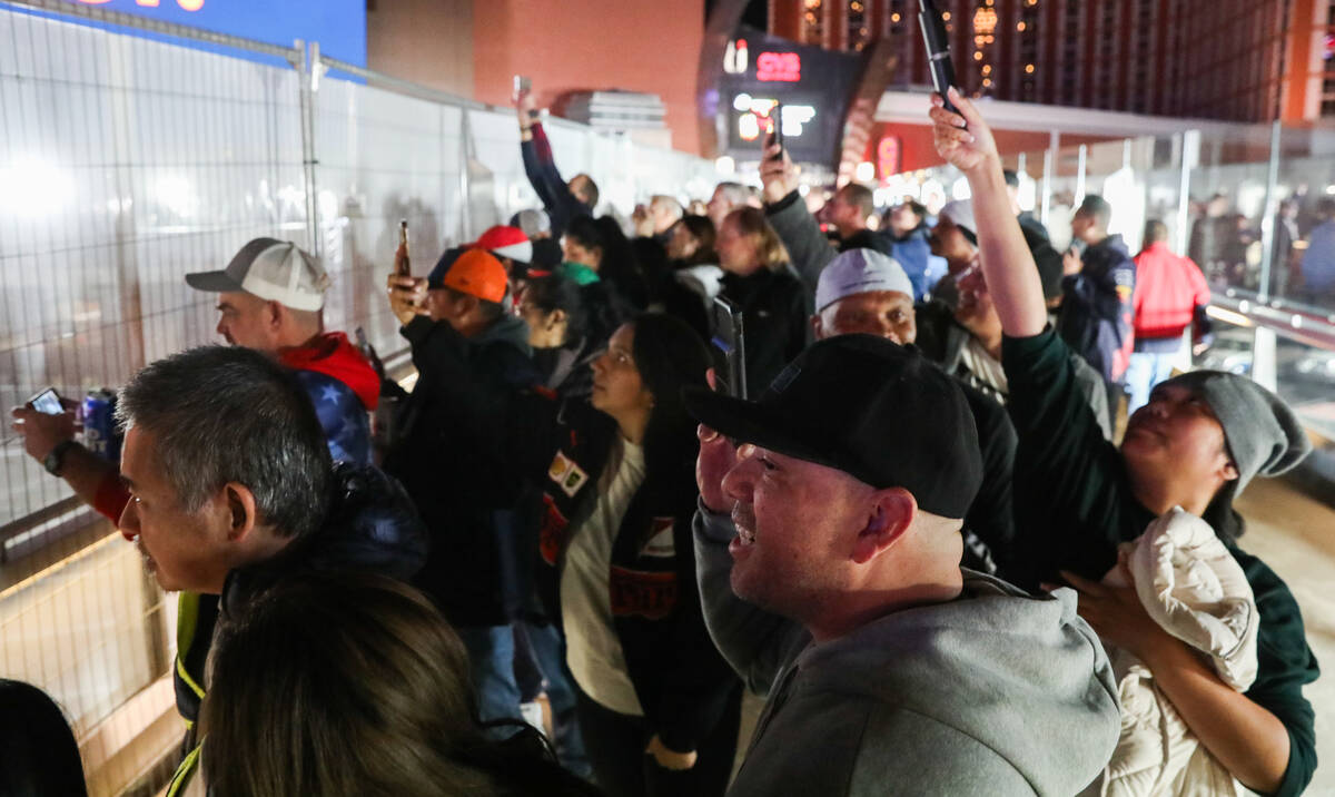 Fans watch the final Formula 1 Las Vegas Grand Prix race through a protective barrier on Saturd ...