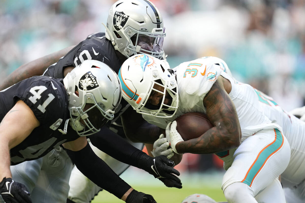 Miami Dolphins running back Raheem Mostert (31) is tackled by Las Vegas Raiders linebacker Robe ...