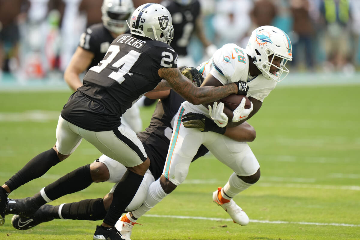 Las Vegas Raiders cornerback Marcus Peters (24) and defensive end Tyree Wilson tackle Miami Dol ...