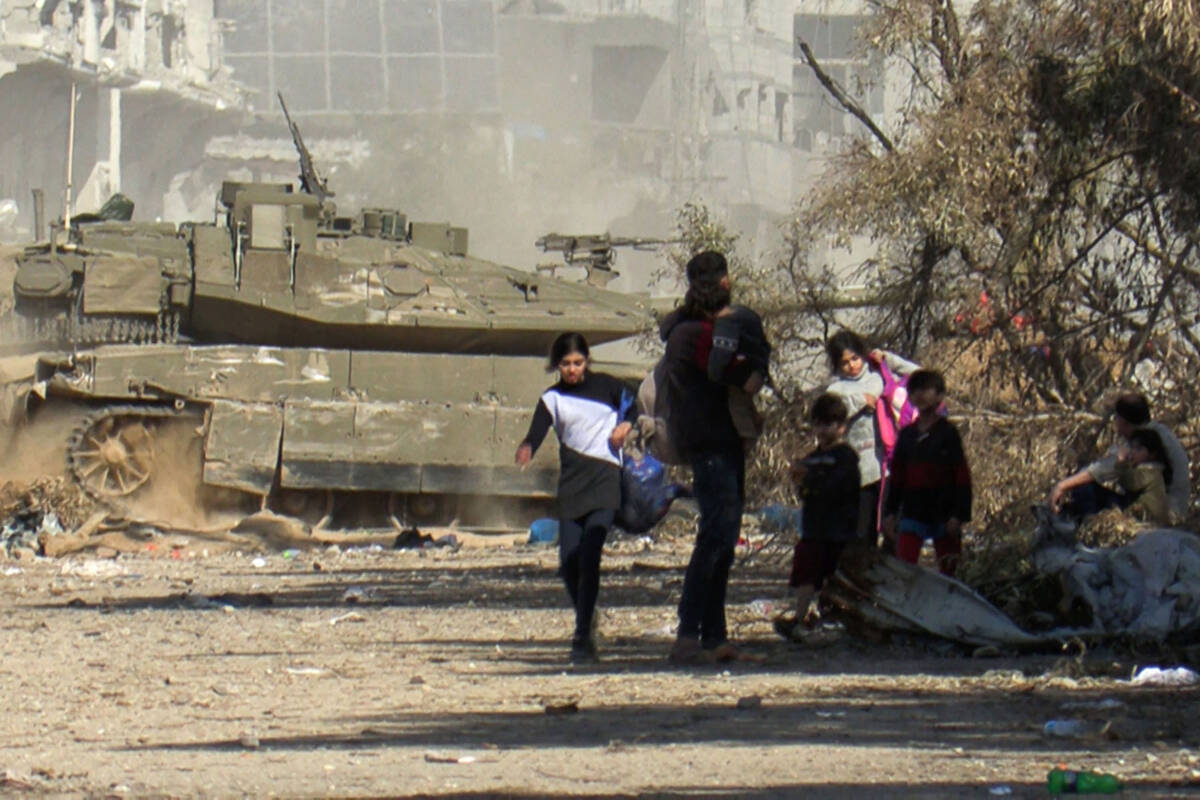 A grab from an AFPTV video shows an Israeli armoured vehicle rolling past Palestinians fleeing ...