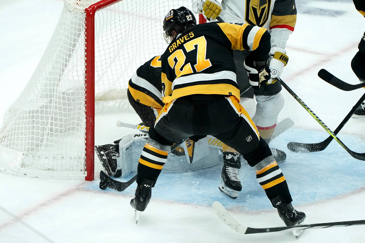 Pittsburgh Penguins' Ryan Graves (27) reaches to pull the puck away from the net in front of go ...