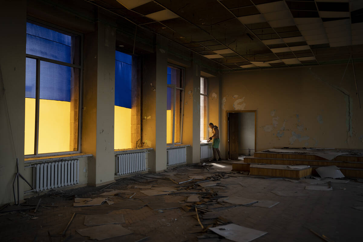 A construction worker looks out of a window of the damaged city council building in Izium, Ukra ...