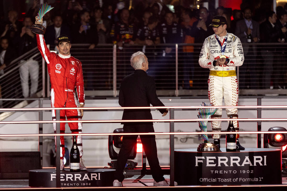 Ferrari driver Charles LeClerc holds up his second place trophy while Red Bull Racing driver Ma ...