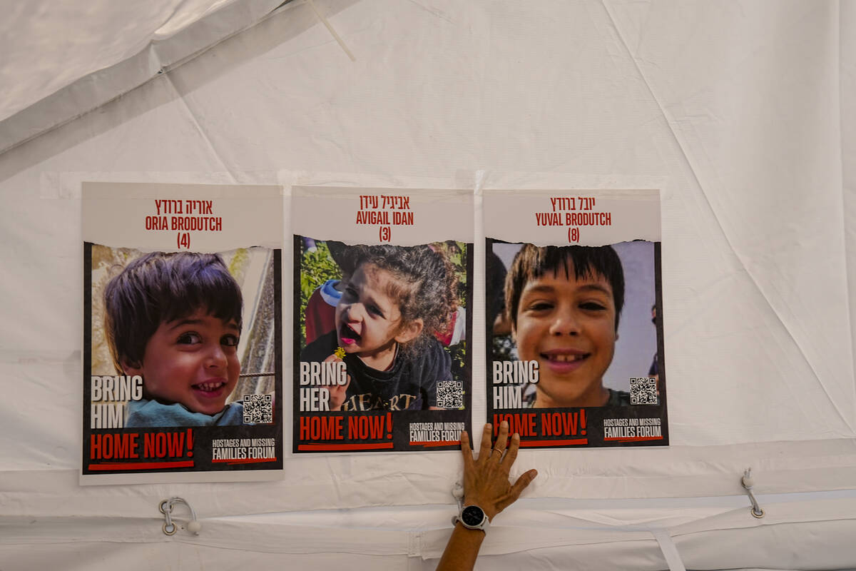 A woman plasters photos of Israeli children from Kibbutz Afar Azza missing and held captive in ...