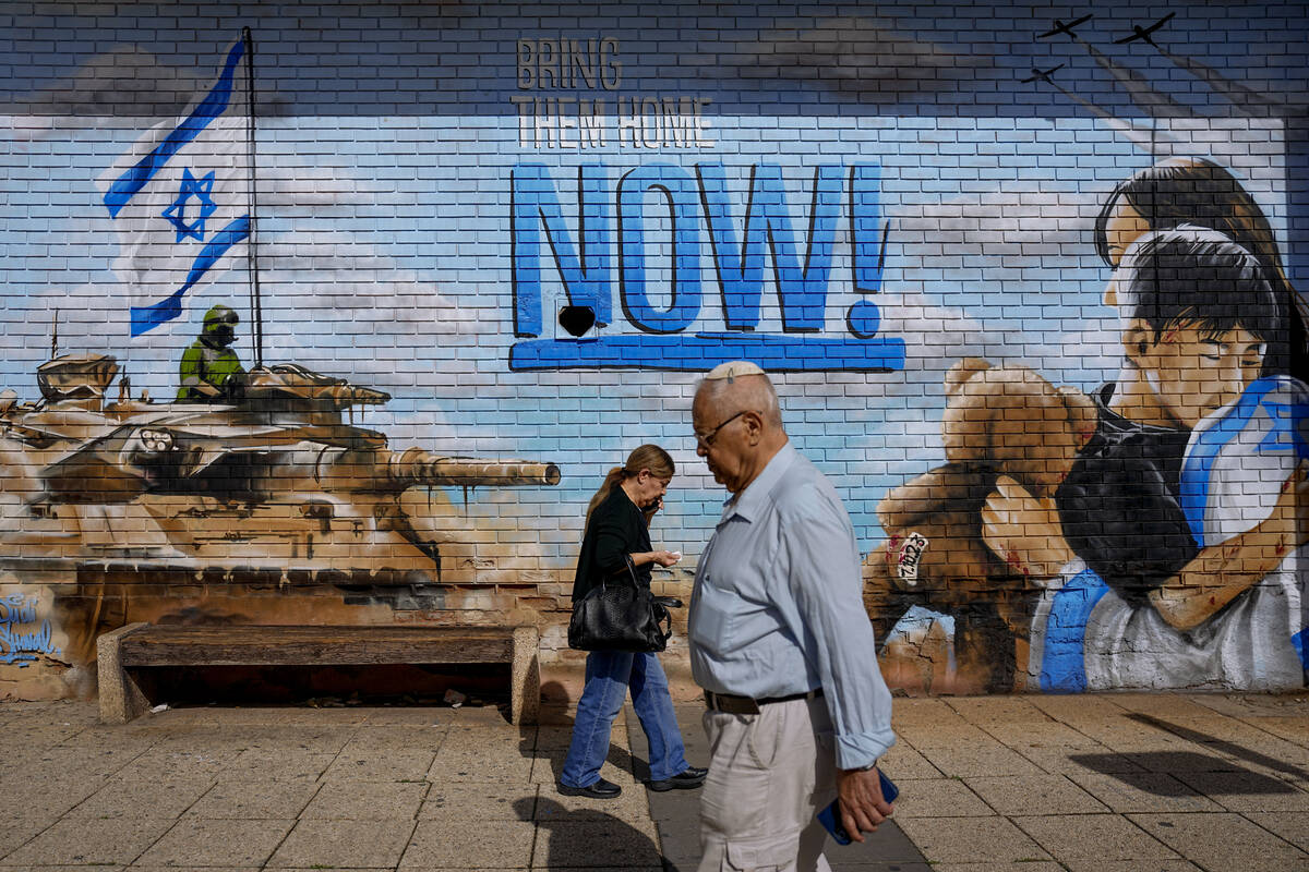 People walk past graffiti calling for the return of the hostages kidnapped during the Oct. 7 Ha ...