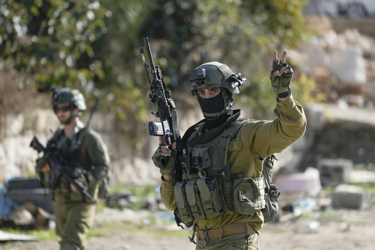 An Israeli soldier flashes a V-sign in Balata, a Palestinian refugee camp in Nablus, West Bank, ...