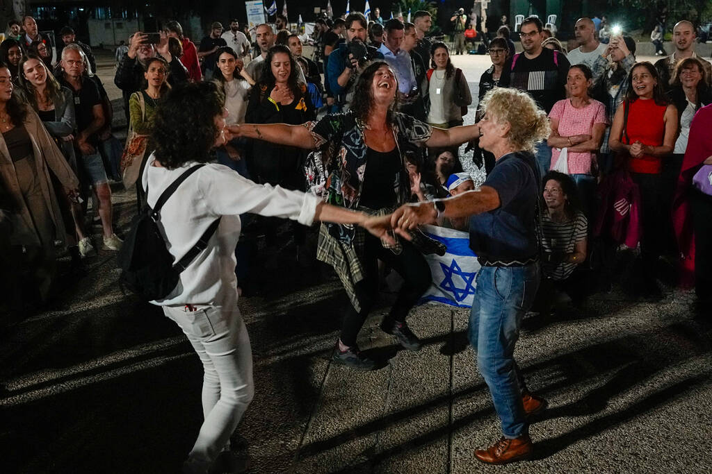 People react as they hear the news of the release of 13 Israeli hostages held by Hamas in the G ...