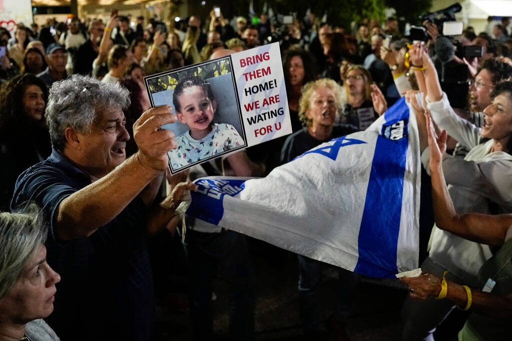 People react as they hear the news of the release of 13 Israeli hostages held by Hamas in the G ...