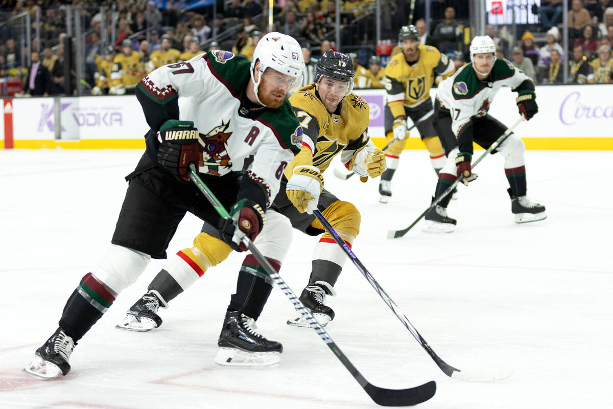 Golden Knights defenseman Ben Hutton (17) reaches for the puck against Coyotes left wing Lawson ...