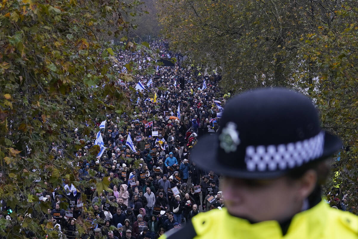 A policewoman stand guard on a bridge as an anti-Semitism demonstration with protesters holding ...