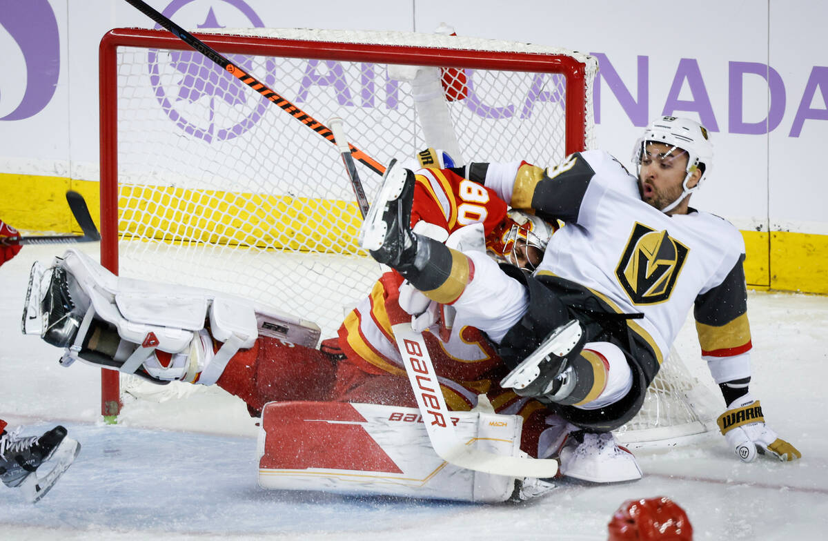 Vegas Golden Knights forward William Carrier, right, slams into Calgary Flames goalie Daniel Vl ...