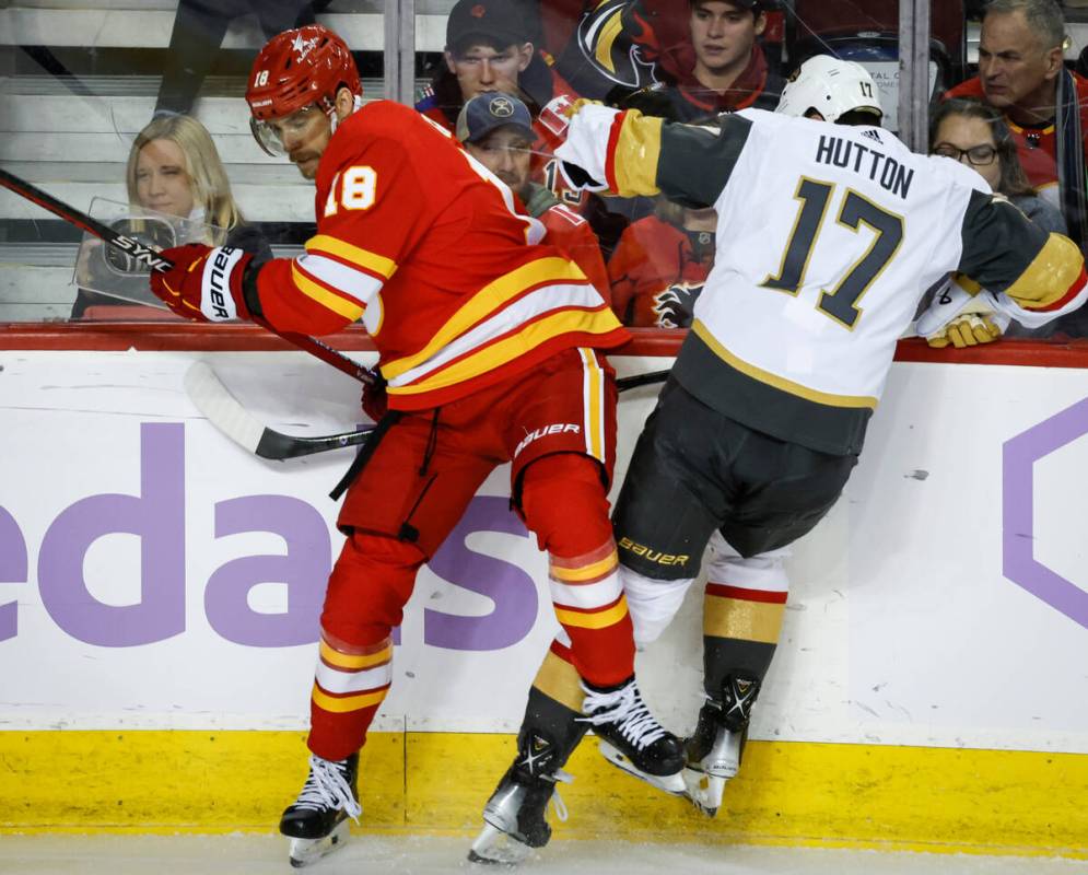 Vegas Golden Knights defenseman Ben Hutton, right, is checked by Calgary Flames forward A.J. Gr ...