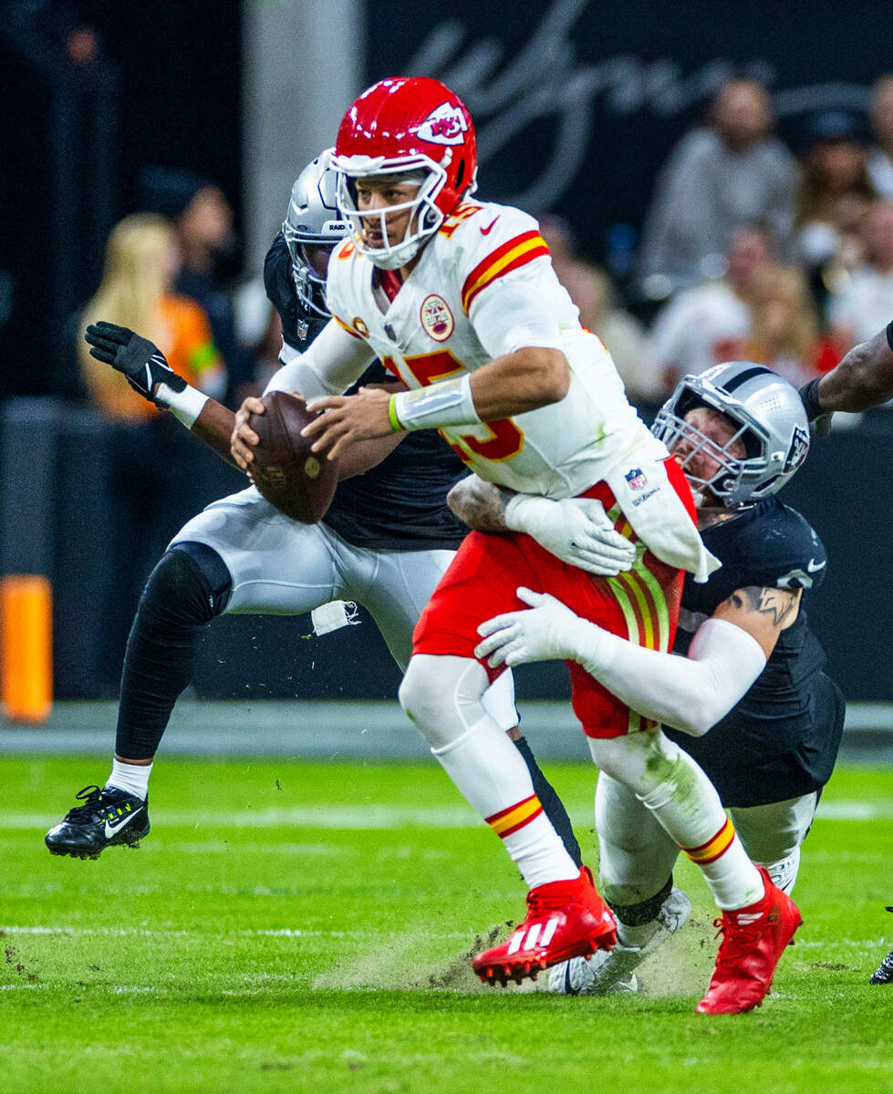 Raiders defensive end Maxx Crosby (98) grabs Kansas City Chiefs quarterback Patrick Mahomes (15 ...