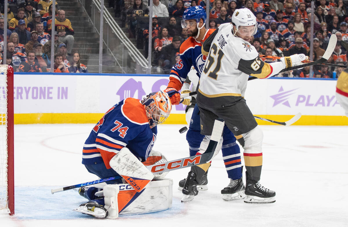 Vegas Golden Knights' Mark Stone (61) and Edmonton Oilers' Darnell Nurse (25) battle in front a ...