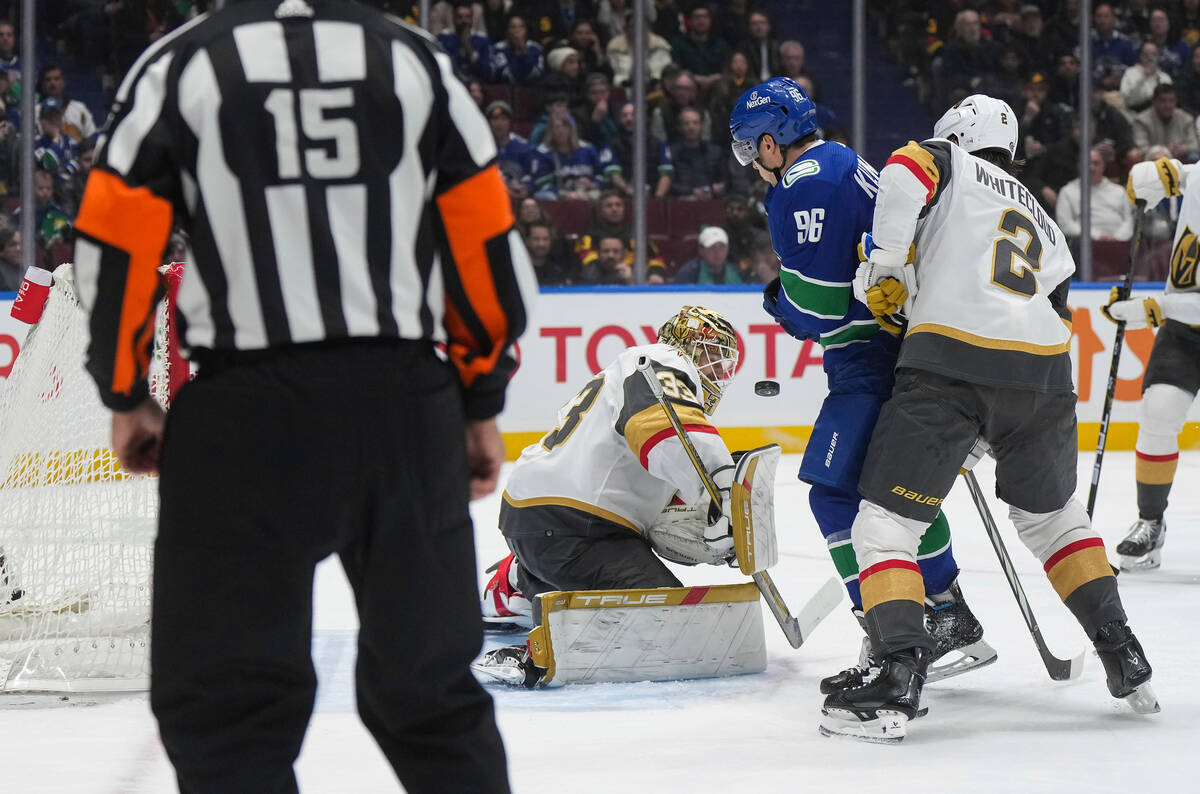 Vegas Golden Knights goalie Adin Hill (33) makes a save as Zach Whitecloud (2) checks Vancouver ...