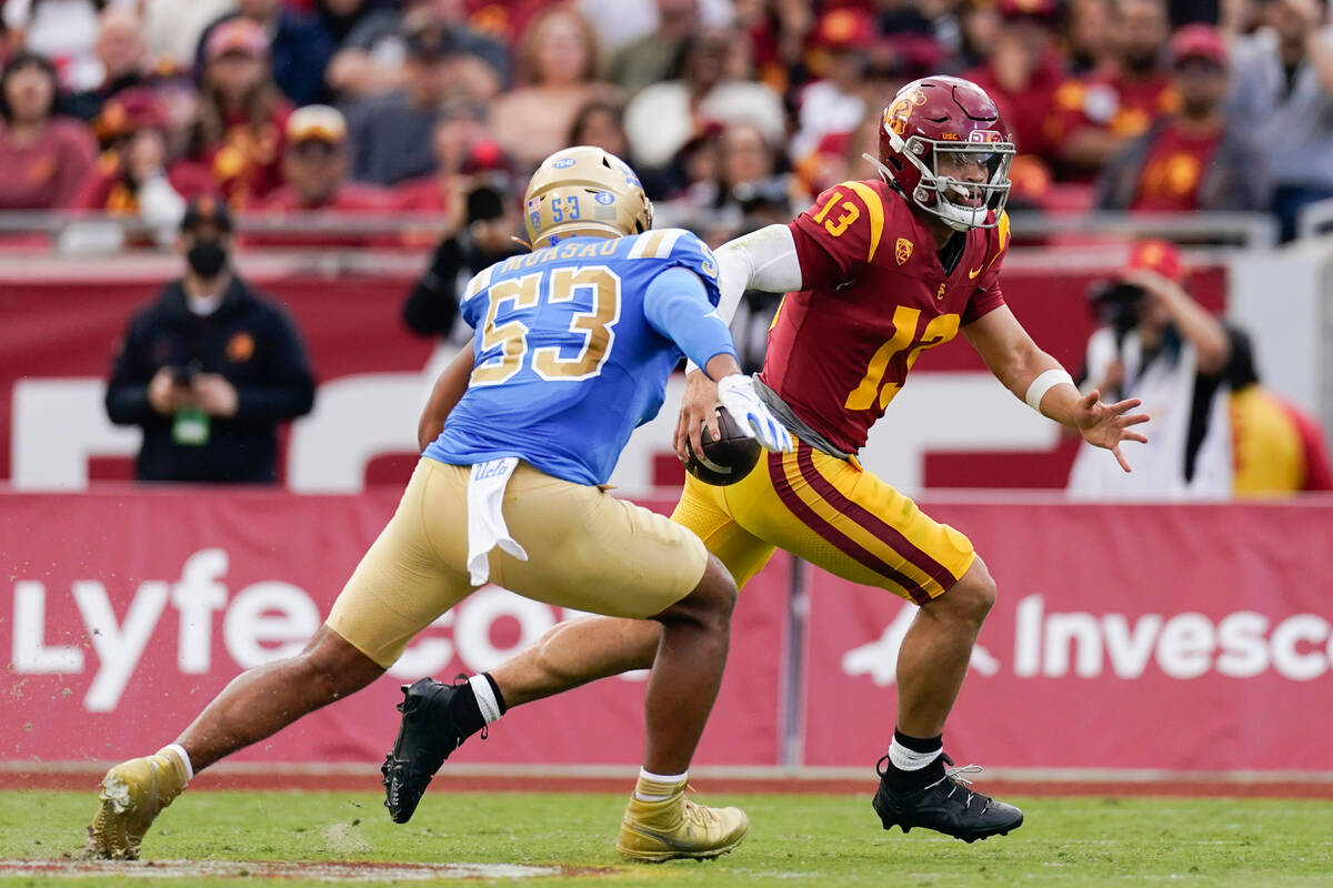 Southern California quarterback Caleb Williams, right, runs as UCLA linebacker Darius Muasau ch ...