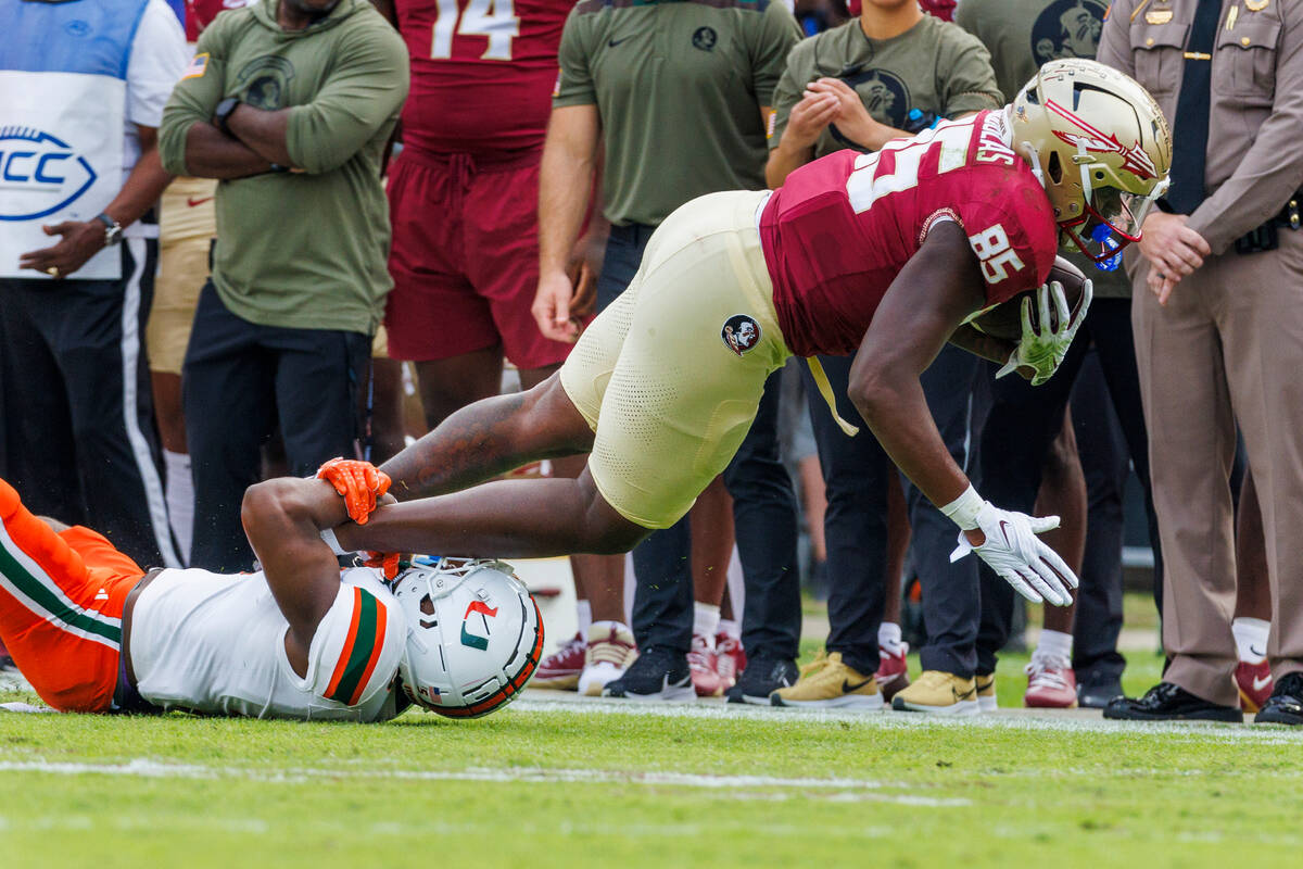 Florida State tight end Markeston Douglas (85) is tackled by Miami safety Kamren Kinchens, bott ...