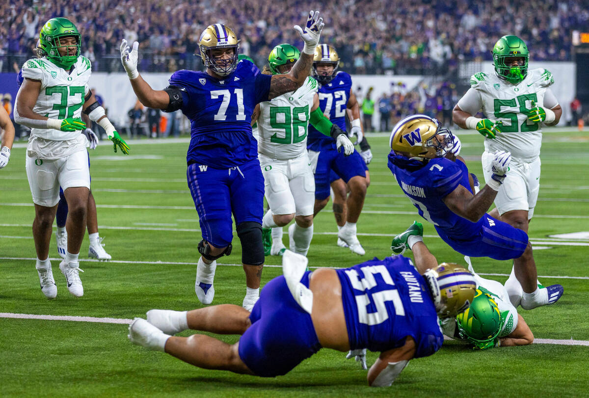 Washington Huskies running back Dillon Johnson (7) falls over Oregon Ducks defensive back Evan ...