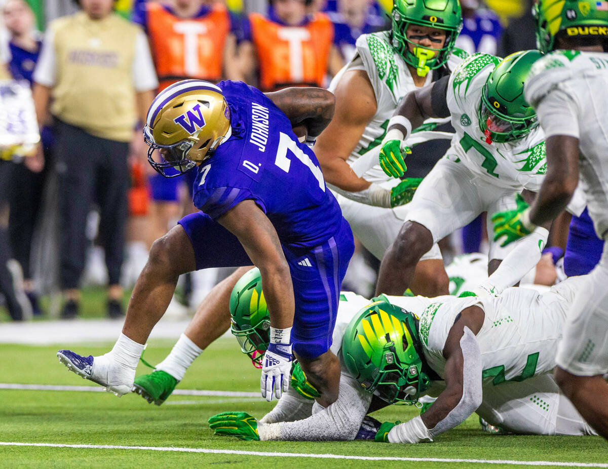 Washington Huskies running back Dillon Johnson (7) works to break and Oregon Ducks tackle durin ...