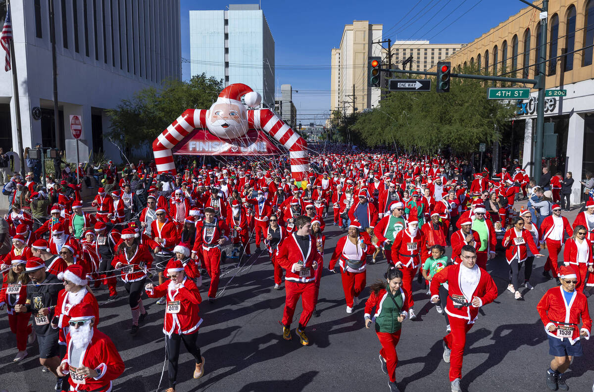 Participants in the 5K run leave the starting line during the Las Vegas Great Santa Run through ...