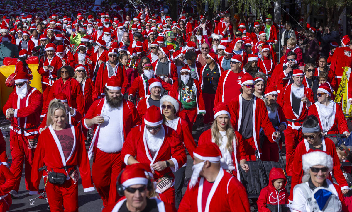 Participants in the 5K run leave the starting line during the Las Vegas Great Santa Run through ...