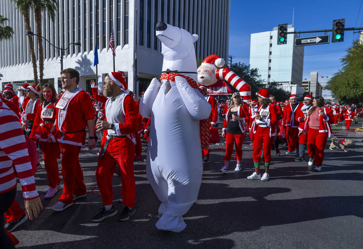 Participants including a polar bear start the 5K run during the Las Vegas Great Santa Run throu ...