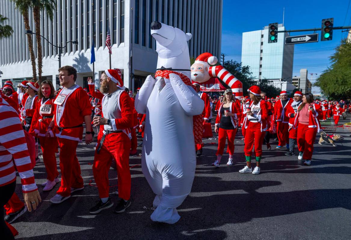 Participants including a polar bear start the 5K run during the Las Vegas Great Santa Run throu ...