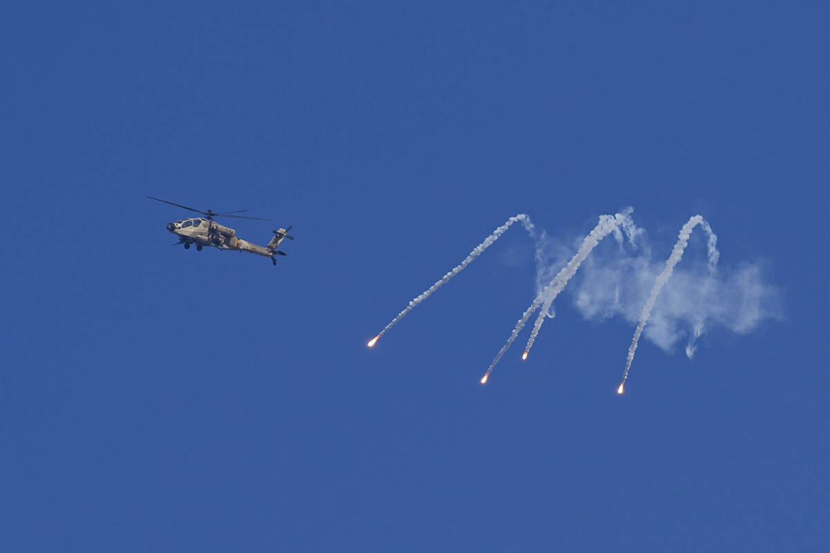 An Israeli military helicopter releases flares over the Israel-Gaza border as seen from souther ...