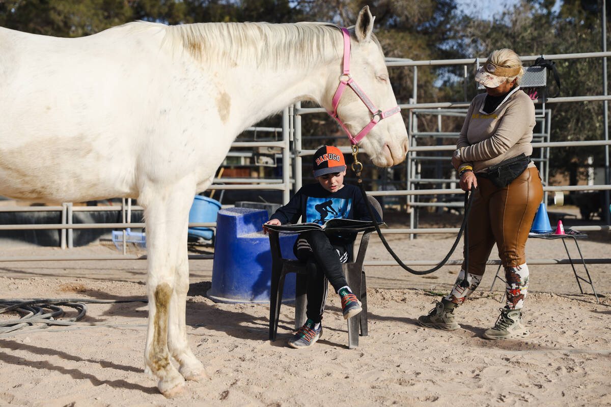 Jude Oles, 10, reads to Lagertha as Esther Hillner looks on at Talisman Farm in Las Vegas, Sund ...