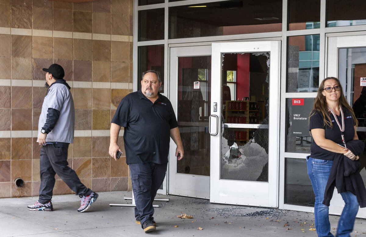 Personnel walk from the UNLV Bookstore with shattered front door glass following the shooting y ...