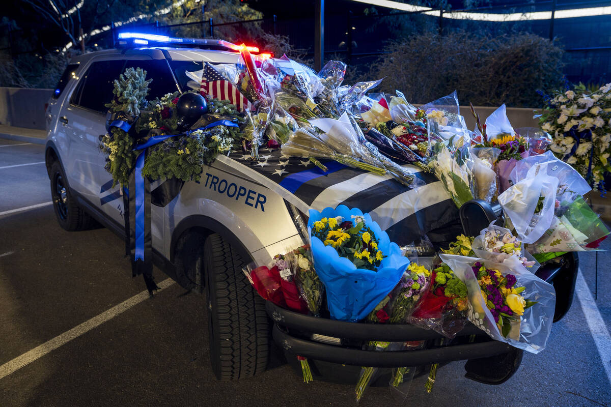 A patrol vehicle is covered in flowers dedicated to Nevada Highway Patrol troopers Sgt. Michael ...