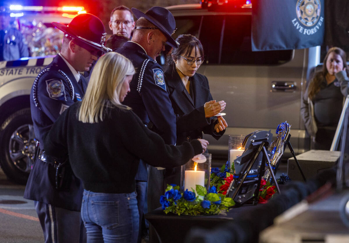 Trooper's wives Vanessa Abbate and Arlene Felix light candles during a candlelight vigil for Ne ...