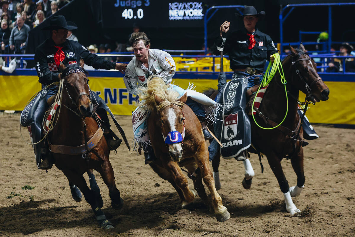 Pickup riders surround Keenan Hayes to help him off of Lil Red Hawk during round one of barebac ...