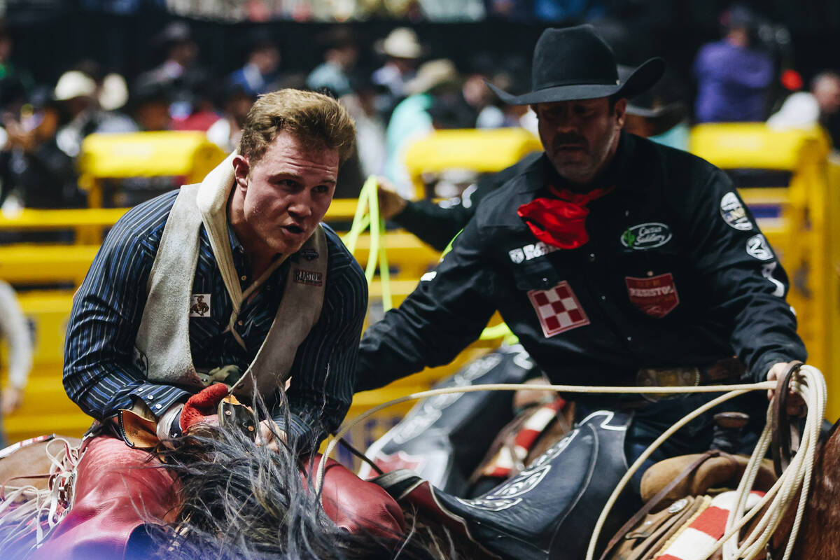 A pickup man helps Dean Thompson off of his ride after his round one bareback ride during NFR a ...