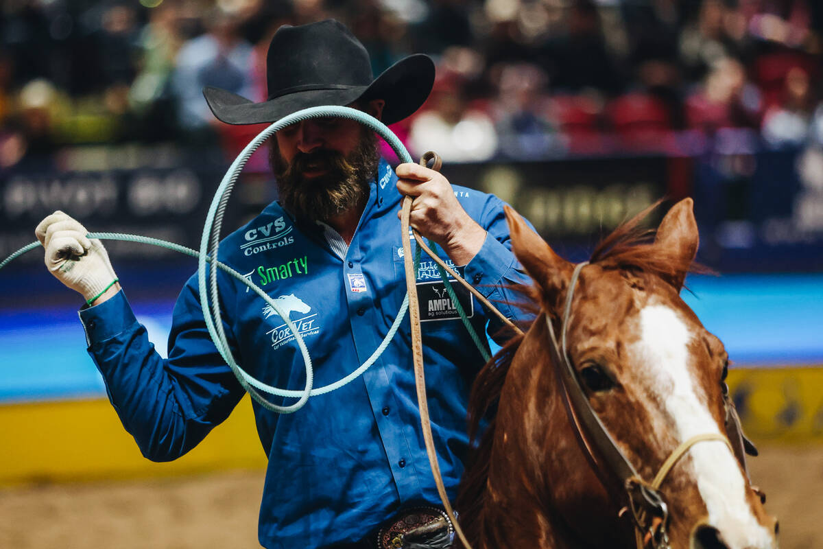 Team roping heeler Jeremy Buhler ropes a calf during National Finals Rodeo at the Thomas & ...