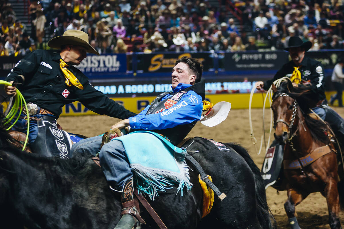 Jess Pope gets help from the pickup men during day three of the National Finals Rodeo at the Th ...