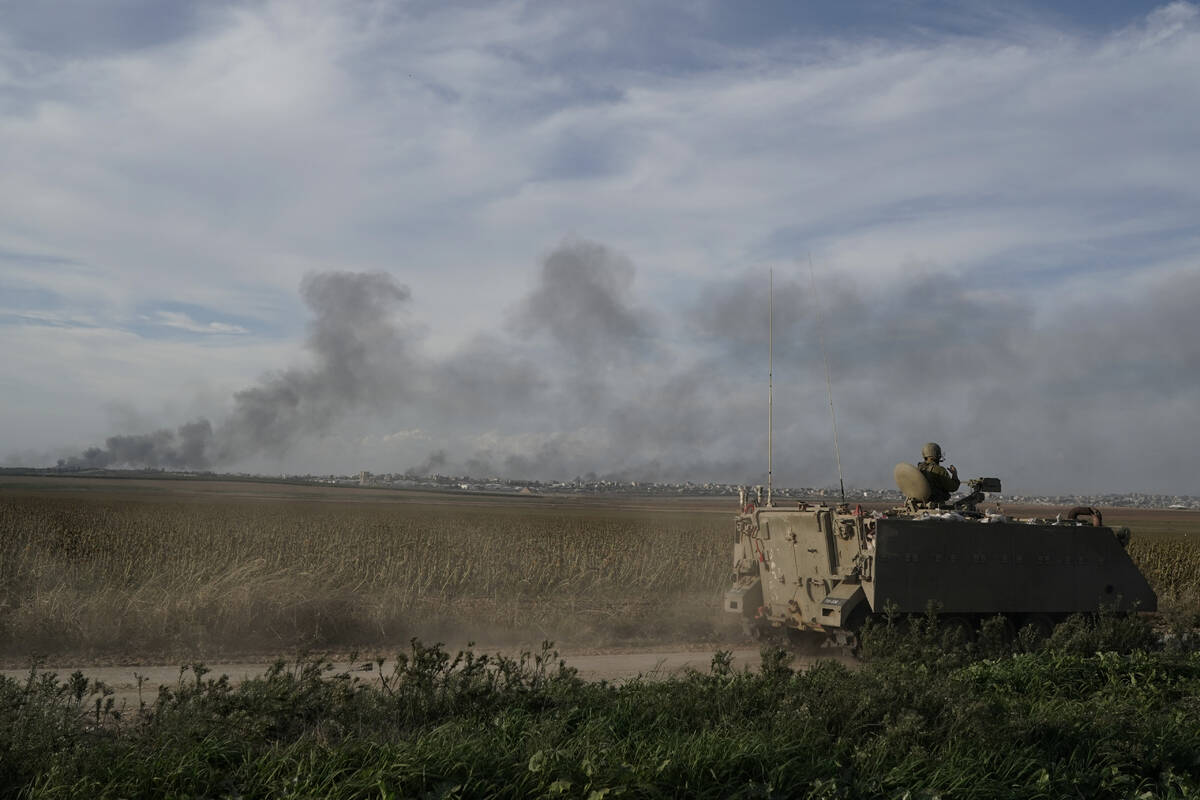 Israeli soldiers patrol as the smoke rises from the Gaza Strip after Israeli strikes on Saturda ...