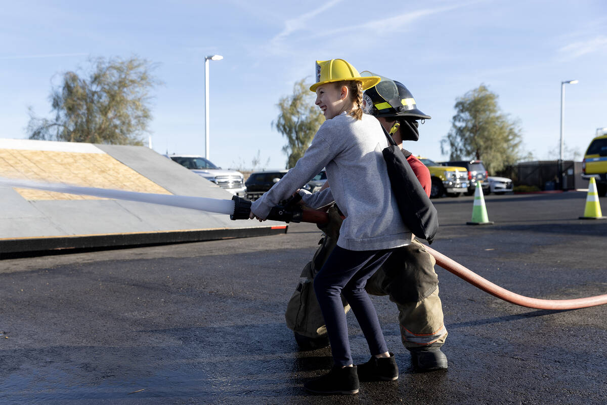 Kiki White, 10, sprays a fire hose with the help of Clark County Explorer Dayton Summers during ...