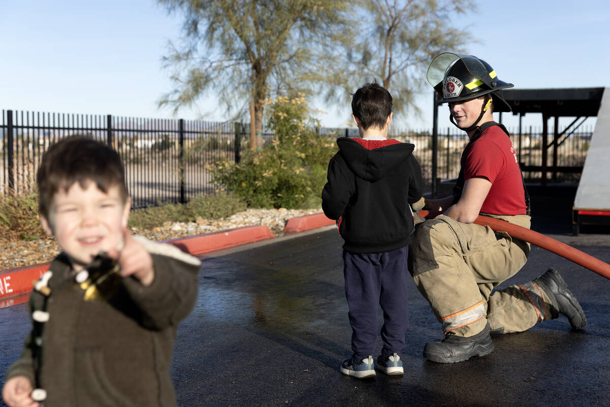 Clark County Explorer Dayton Summers shows Pace Ono, 5, how to use a fire hose during a communi ...