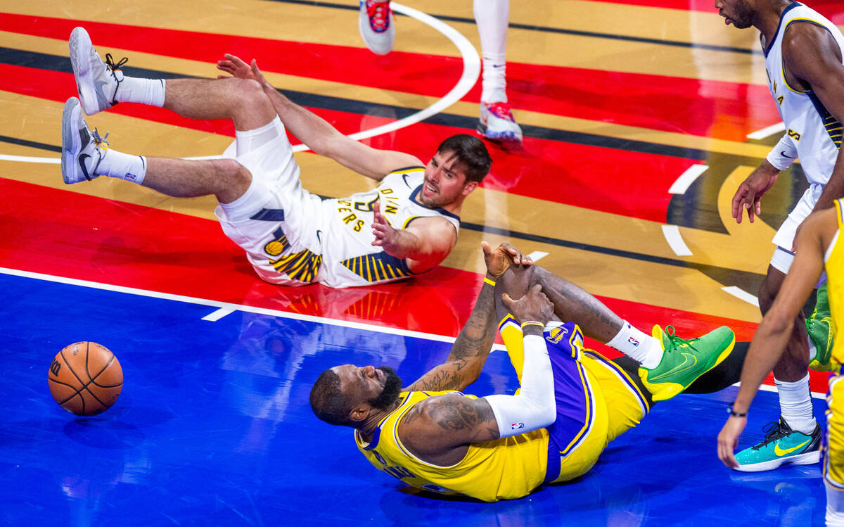 Los Angeles Lakers forward LeBron James (23) grabs his knee after a collision with Indiana Pace ...