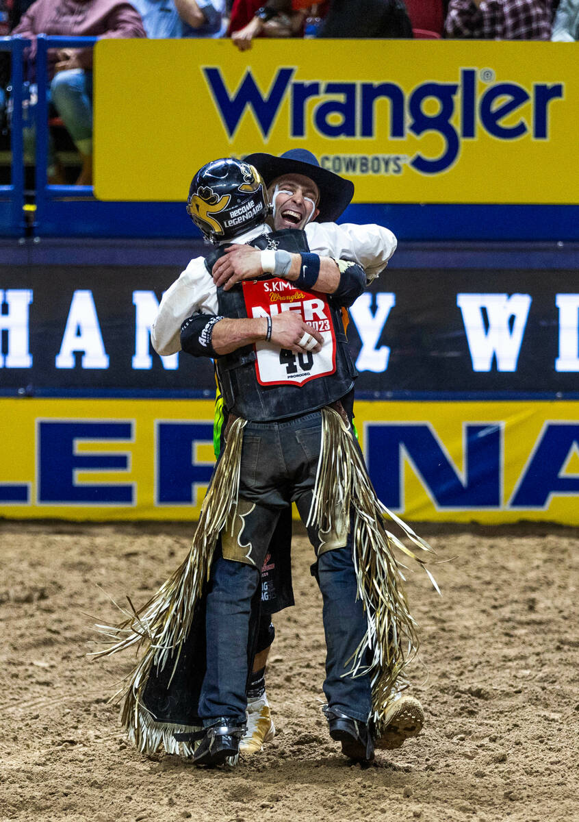 Bullfighter Dusty Tuckness hugs Sage Kimzey after taking first place in Bull Riding during day ...