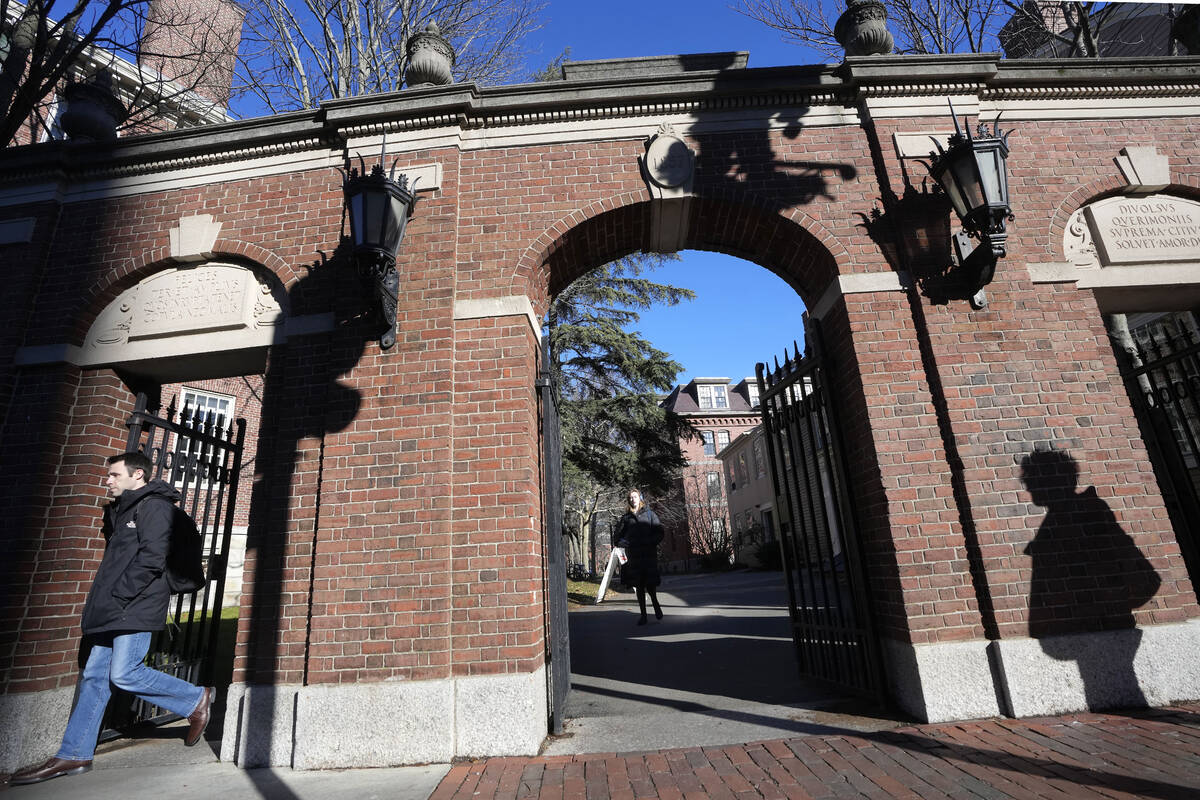 Passers-by walk near an entrance to Harvard University, Tuesday, Dec. 12, 2023, in Cambridge, M ...