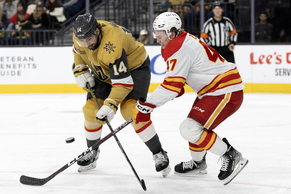 Golden Knights defenseman Nicolas Hague (14) and Flames center Connor Zary (47) battle for the ...